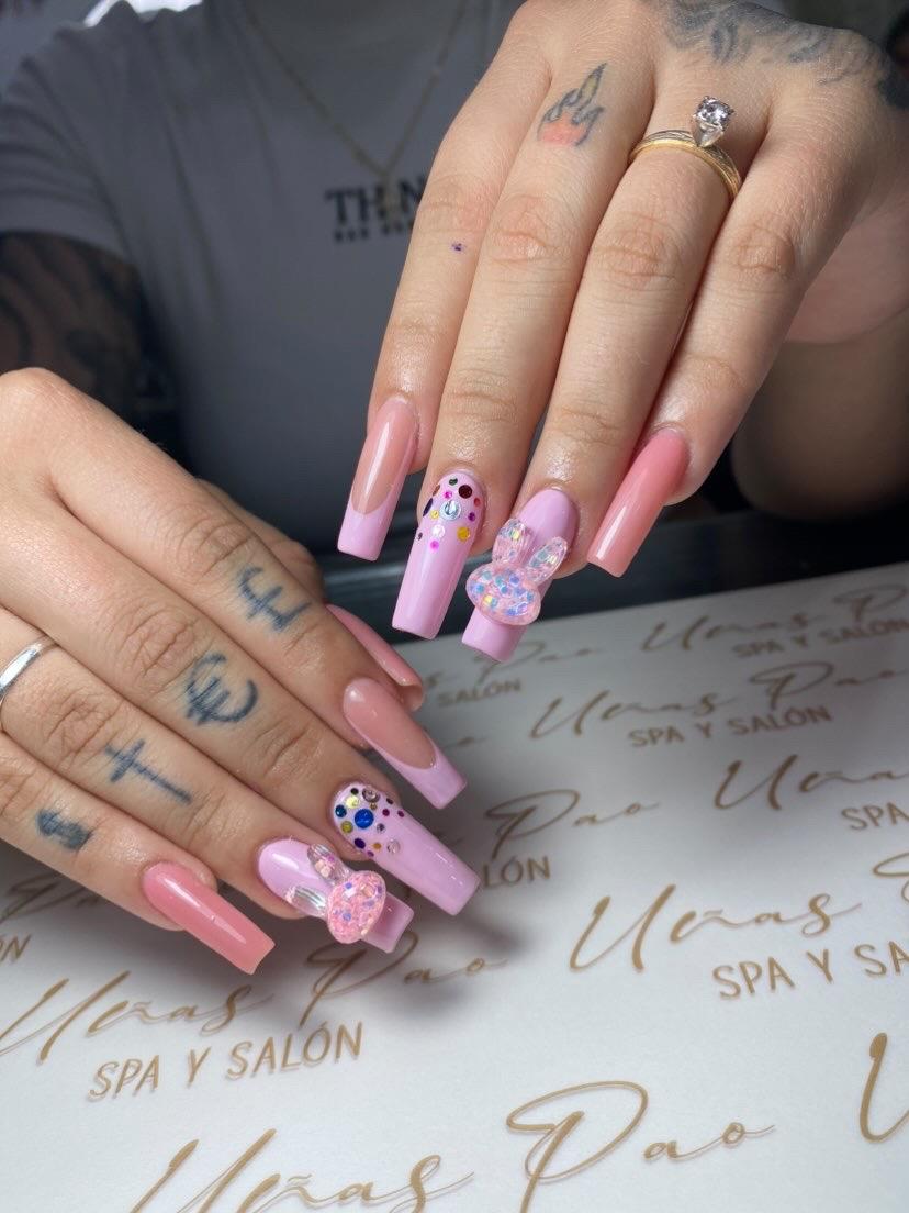 Uñas rosadas con charms y diseños a mano alzada
